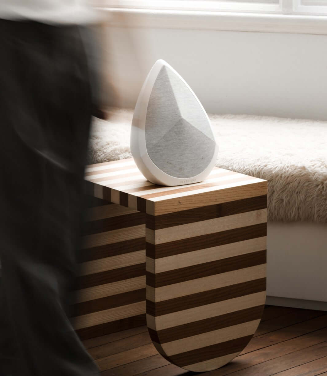 An obsidian white Bluetooth speaker placed on a side table
