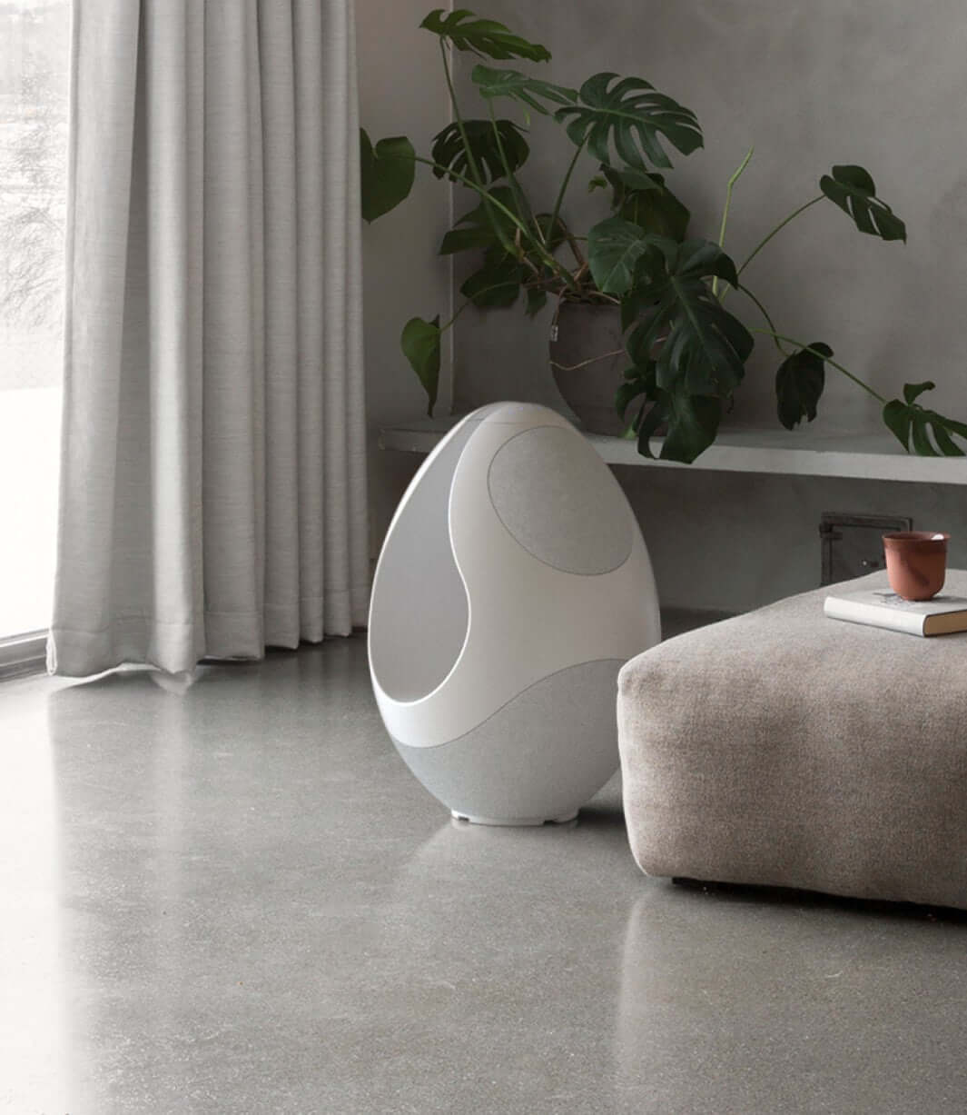 Pantheone I white wireless speaker next to a sofa
