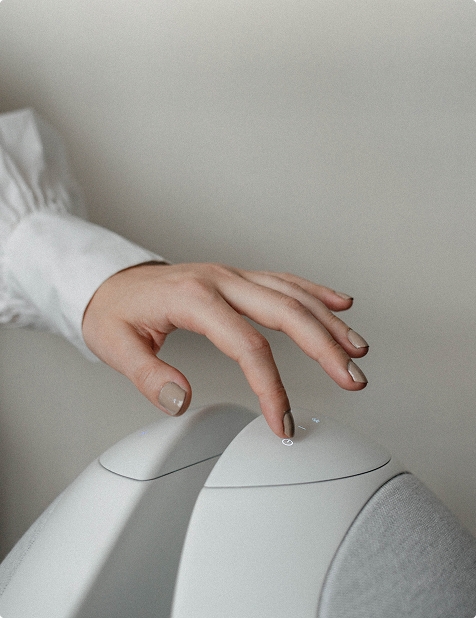 Close-up of the control panel on a Pantheone I speaker, showing a user touching the buttons