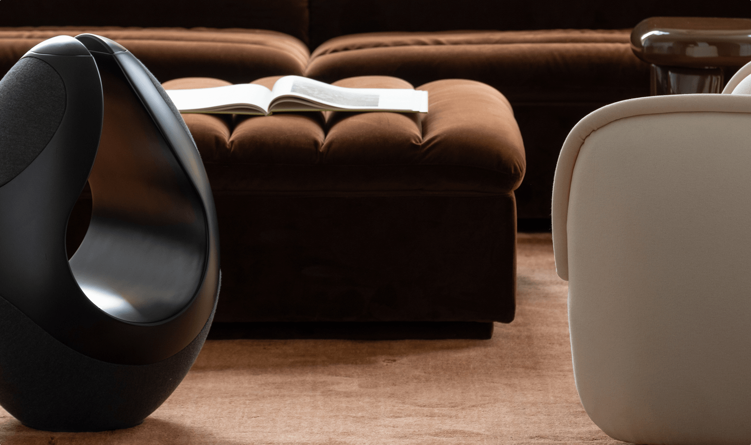 Pantheone I high-end wireless speaker in modern luxury interior beside tufted ottoman and soft lounge seating