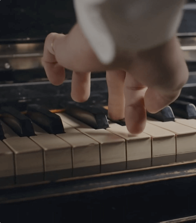 Close-up of a hand playing worn piano keys, focusing on touch and expression.