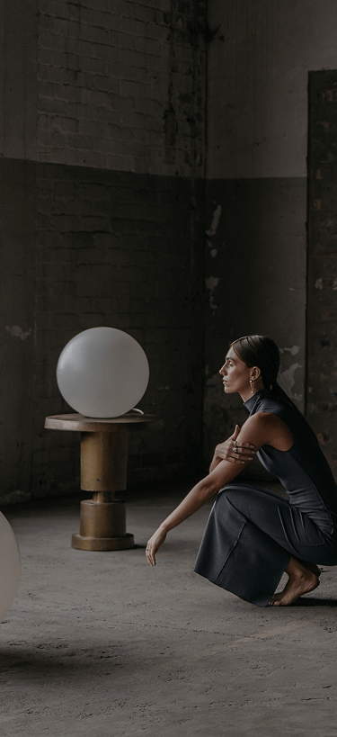 Woman sitting on the floor in a room with large white spheres and a black speaker.
