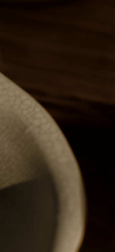 Close-up of ceramic bowls with a crackled glaze finish, resting on a wooden surface in warm light.