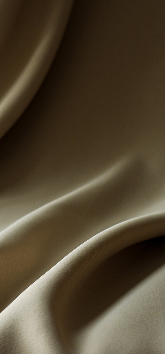 Soft beige fabric with natural folds and light play, creating a sense of movement and elegance.