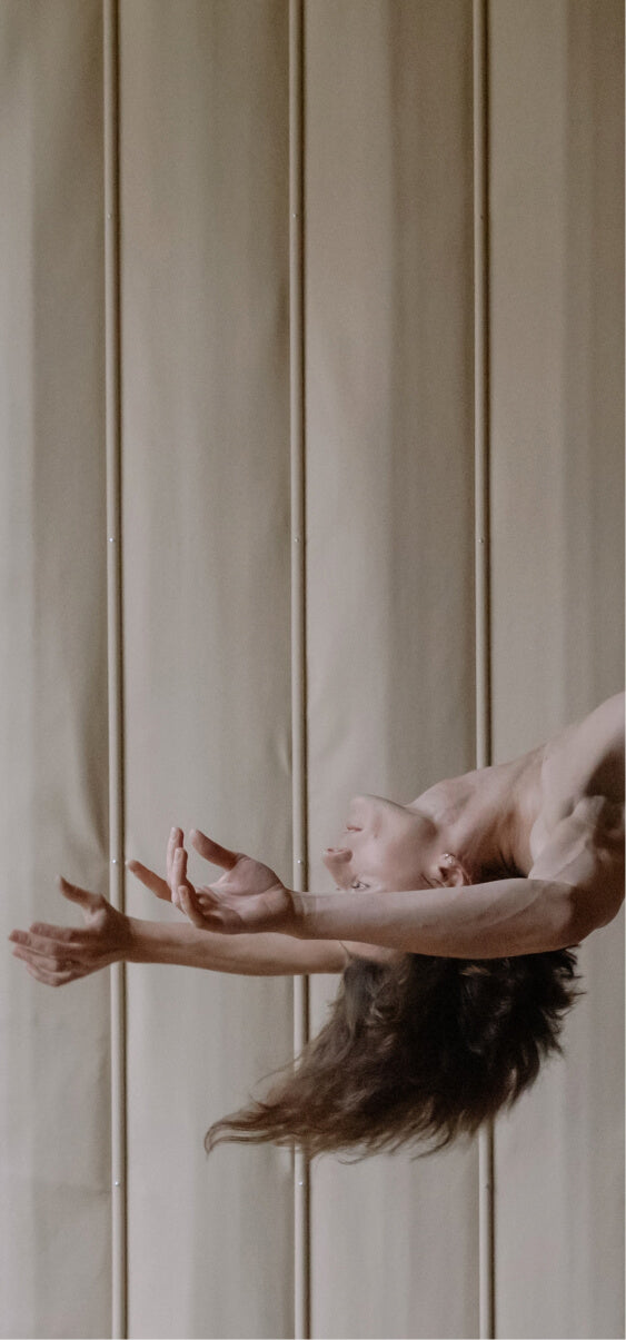 Ballet dancer performing an elegant arabesque pose against a softly lit padded wall.