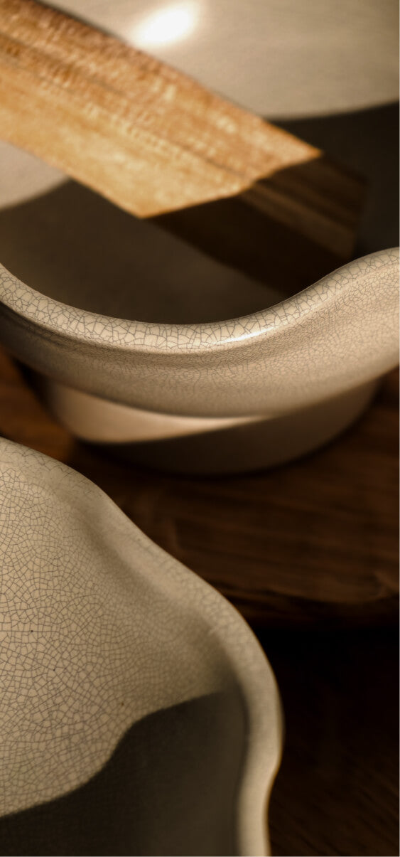 Close-up of ceramic bowls with a crackled glaze finish, resting on a wooden surface in warm light.