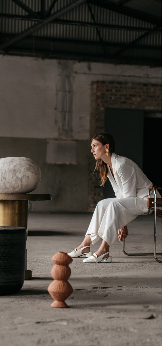 Woman in a white outfit seated in a modern industrial space