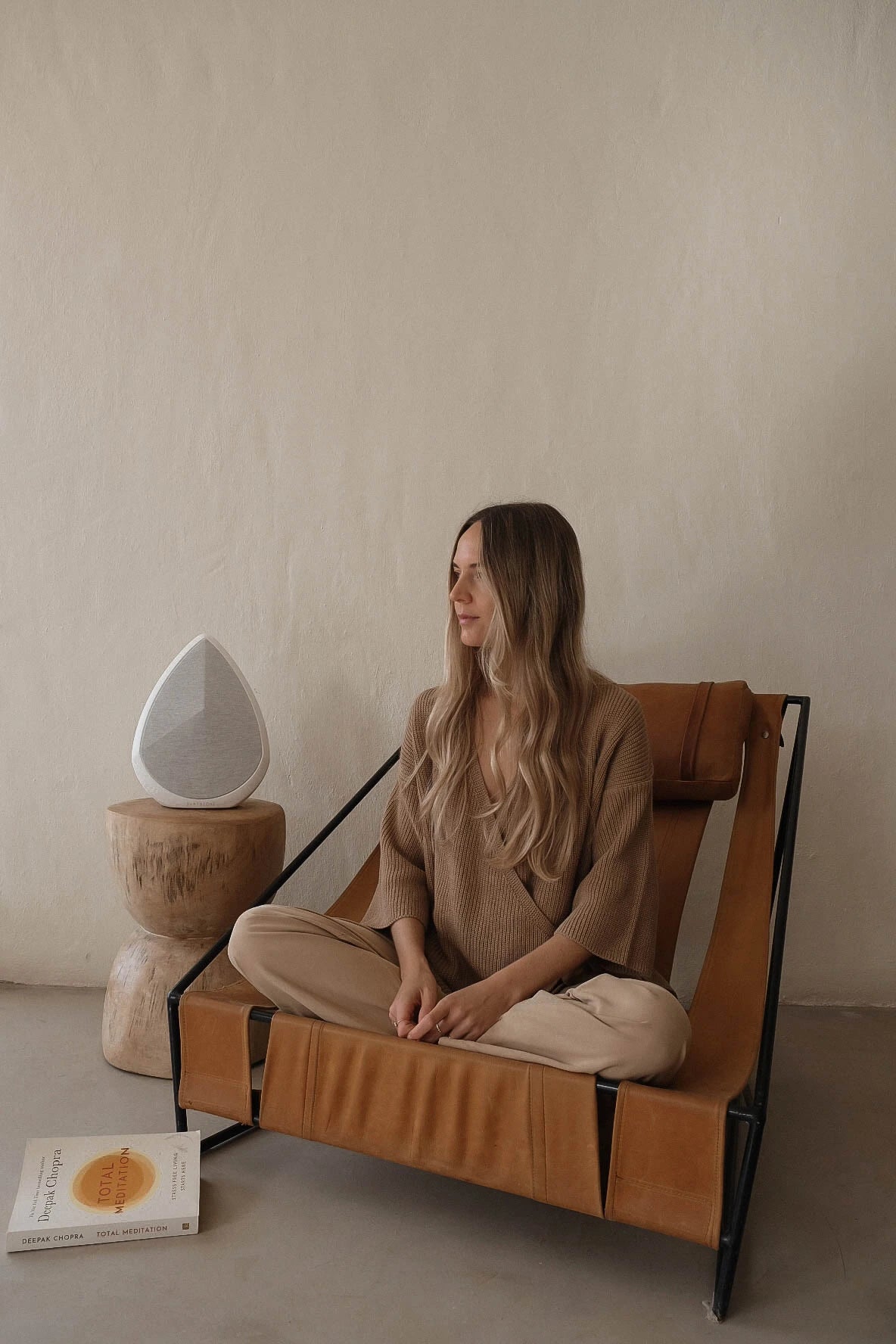 user sits on a stylish chair listening to the obsidian wireless speaker 