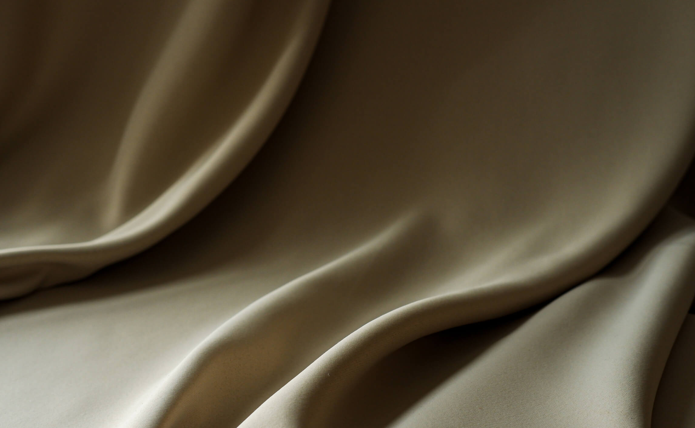 Soft beige fabric with natural folds and light play, creating a sense of movement and elegance.