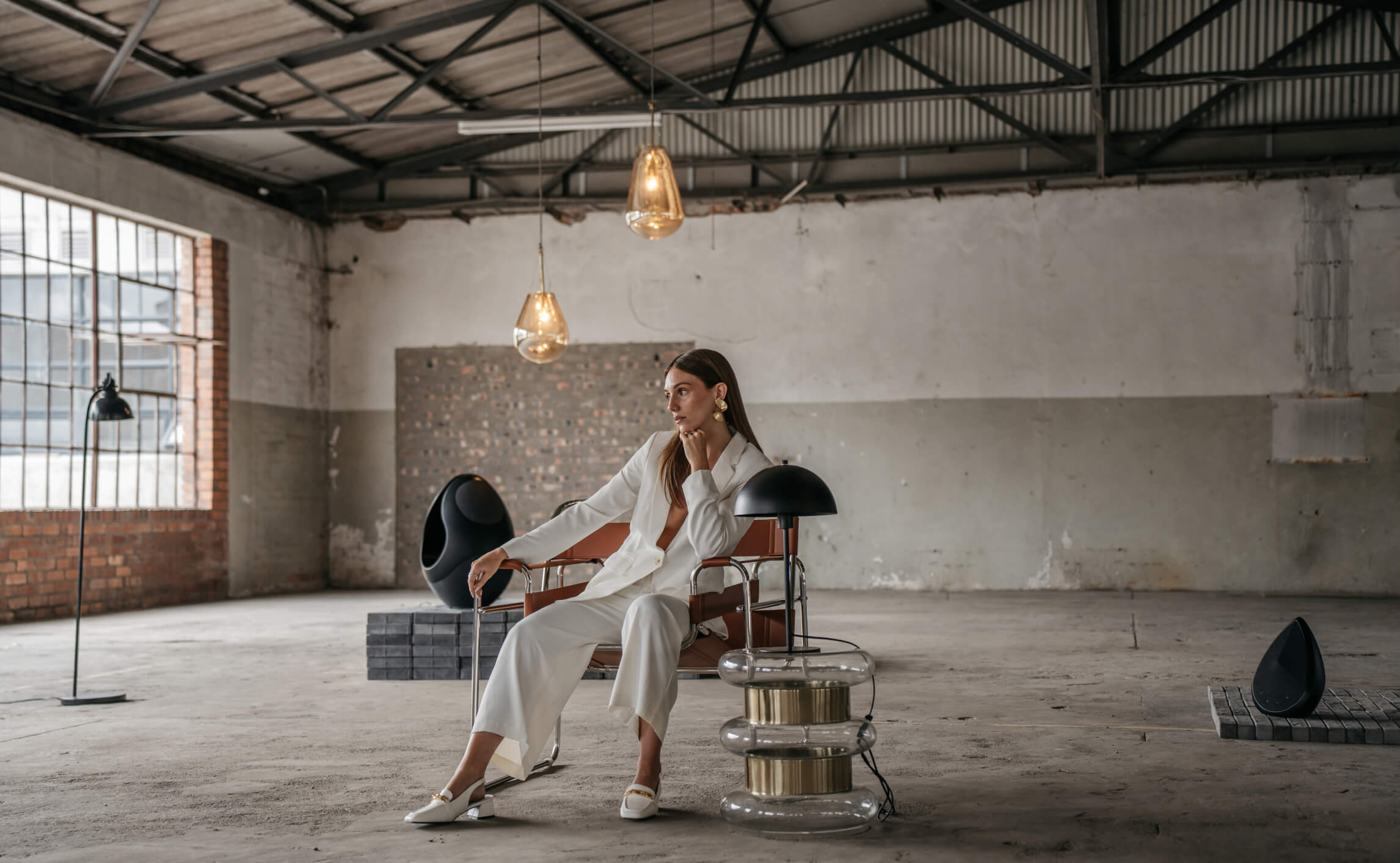 a woman sitting in an industrial room listening to the Pantheone I and the Obsidian speaker