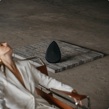 A model seated beside Obsidian speakers in an industrial interior