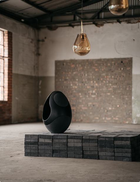 Pantheone I luxury speaker on bricks in an industrial space with a stylish decorative lamp above it 