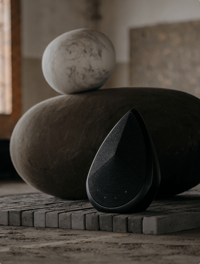 Pantheone Obsidian portable Bluetooth speaker on bricks next to a big stone 