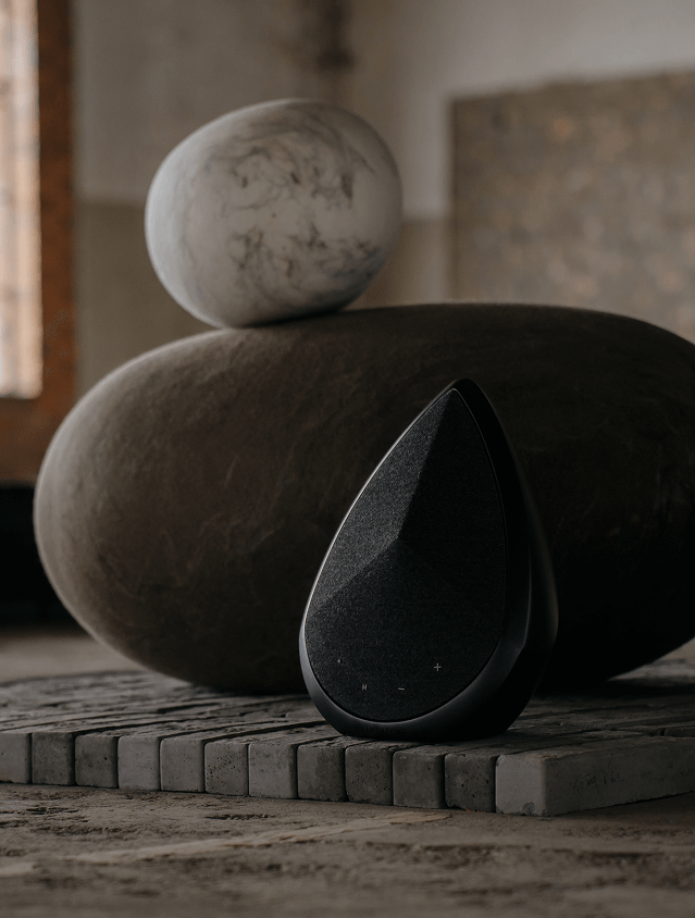 Black Obsidian speaker beside rounded sculptural stones