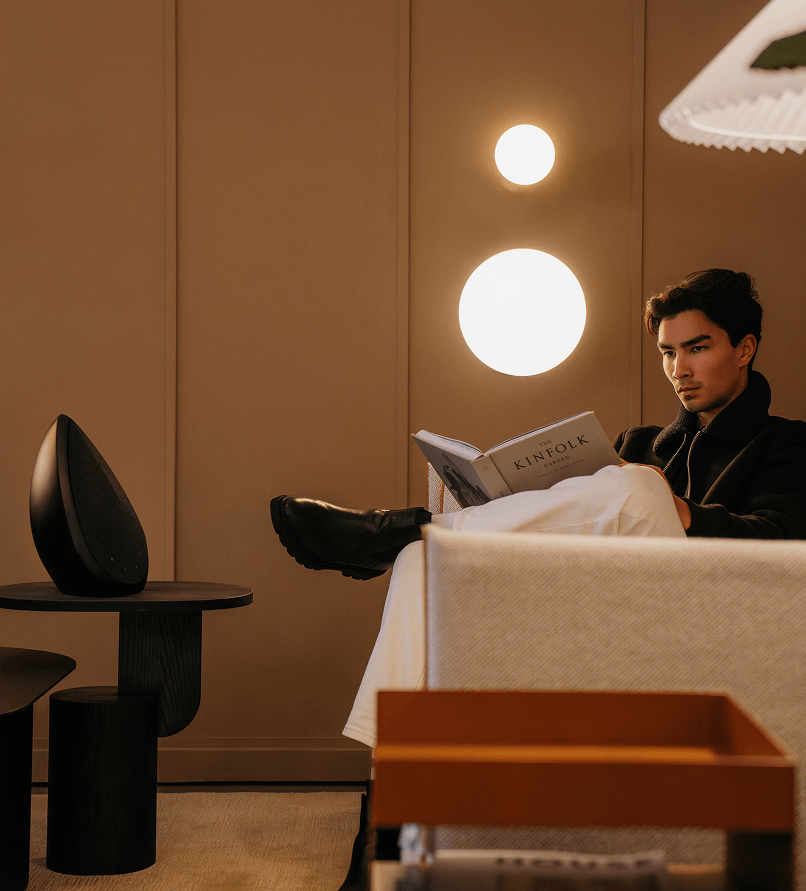 A man reading a book and listening to the Pantheone Obsidian Bluetooth speaker