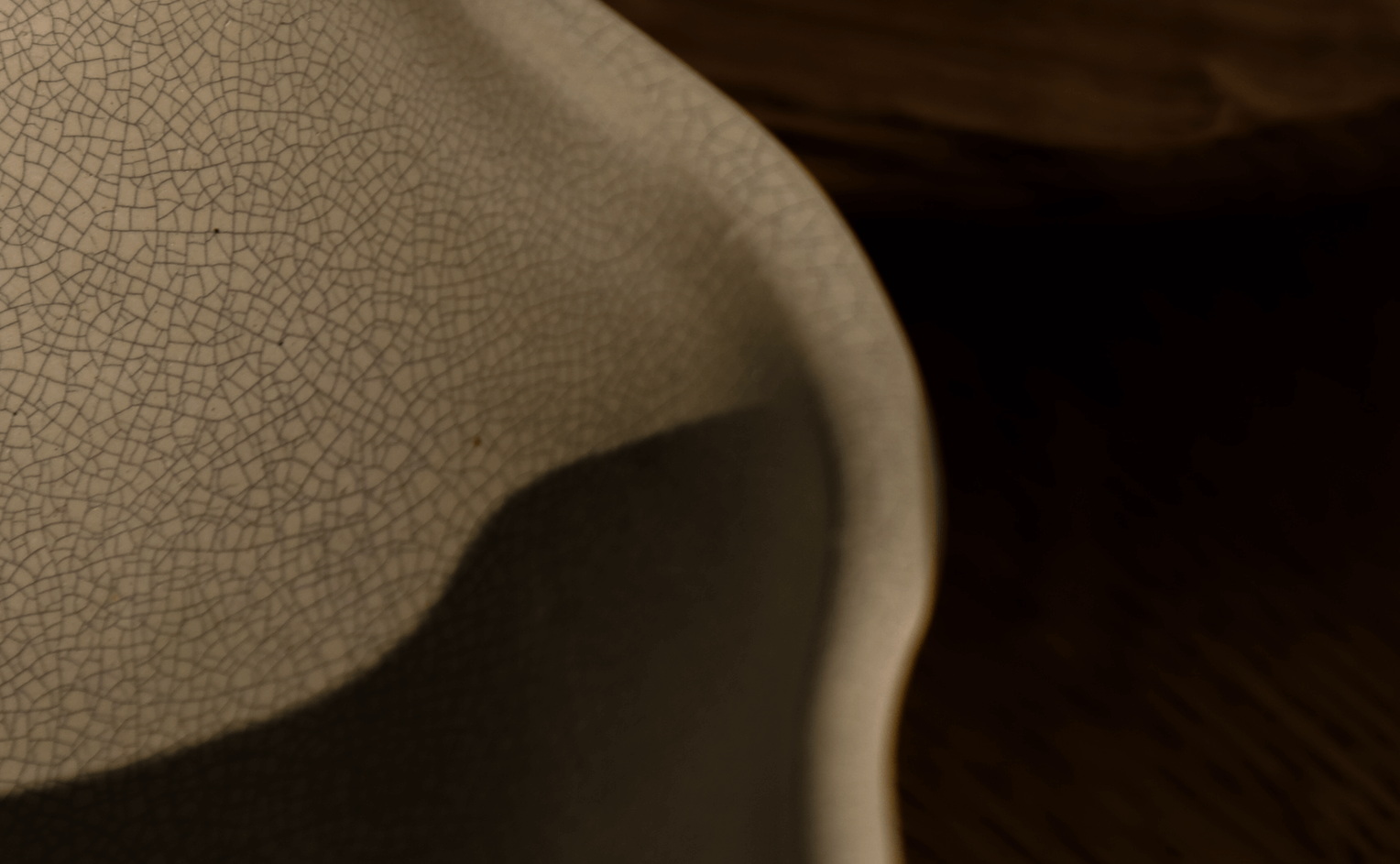 Close-up of ceramic bowls with a crackled glaze finish, resting on a wooden surface in warm light.
