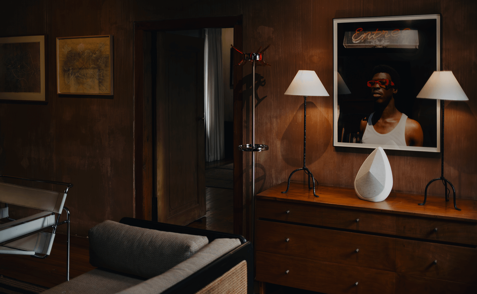 Obsidian wireless designer speaker on a cabinet next to two lights in a dark room  