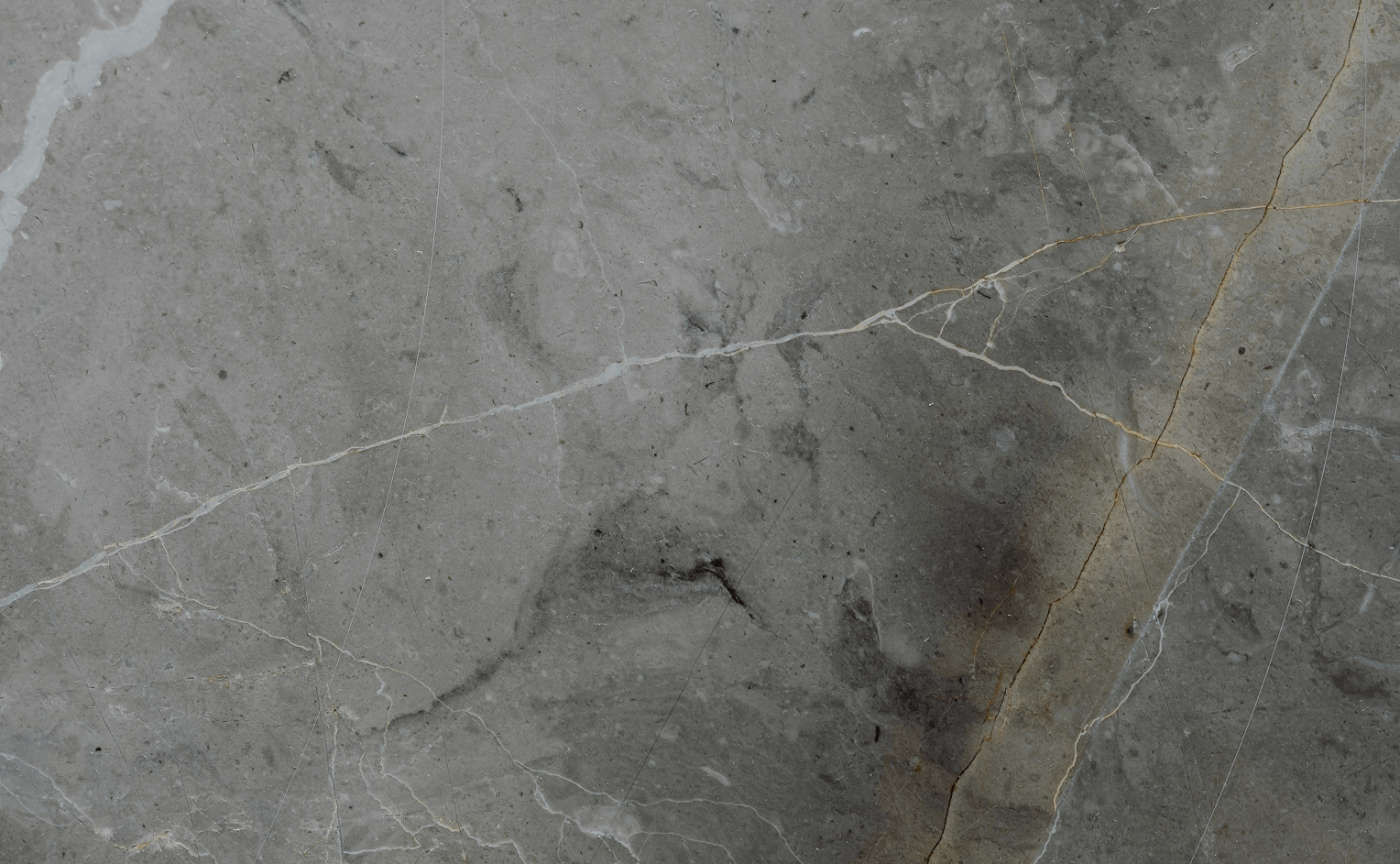 Close-up of grey marble surface with natural veining and subtle cracks.