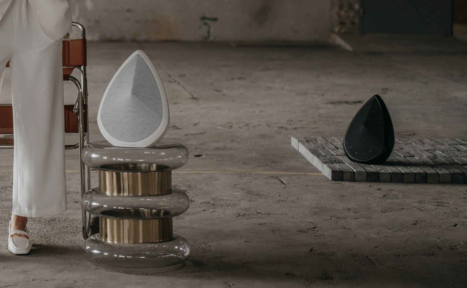 Obsidian white and black wireless speaker on stone platform in curated interior