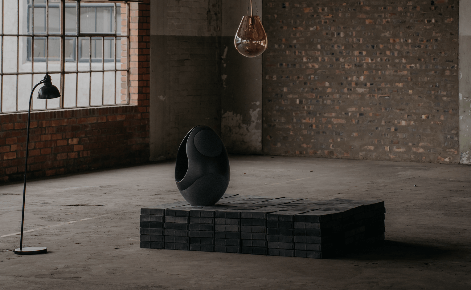 pantheone I black wireless speaker on concrete pedestal with sculptural lighting