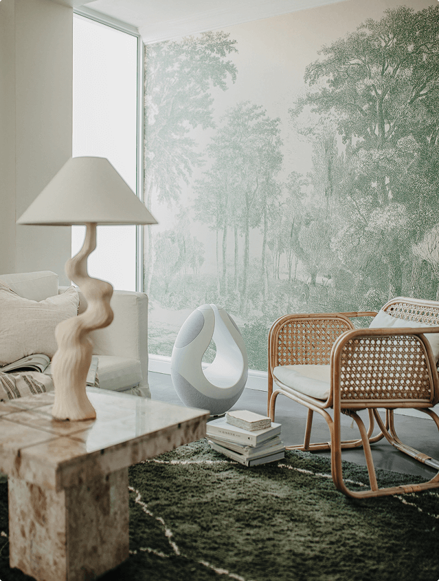 Pantheone I in white luxury speaker in a bright light next to a designer chair 