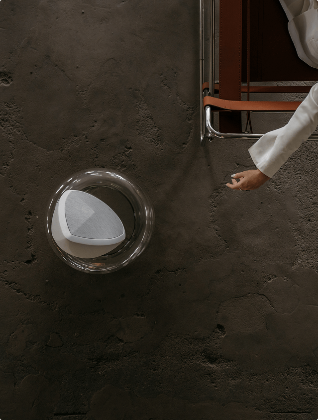 Top view of the Obsidian white designer speaker with a hand reaching to it