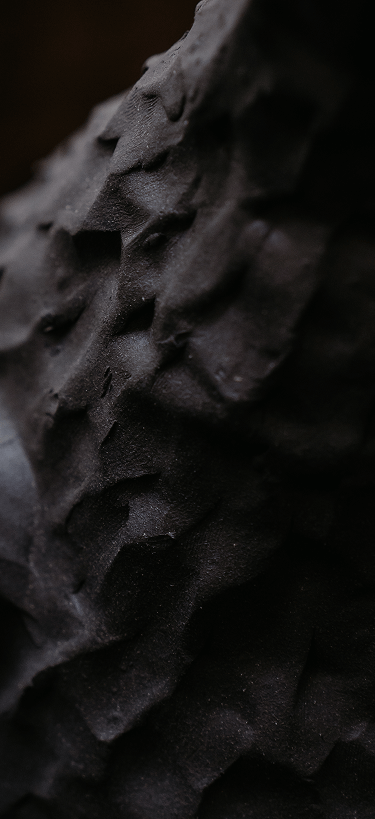 Close-up of rippled black sand with soft light and texture details.
