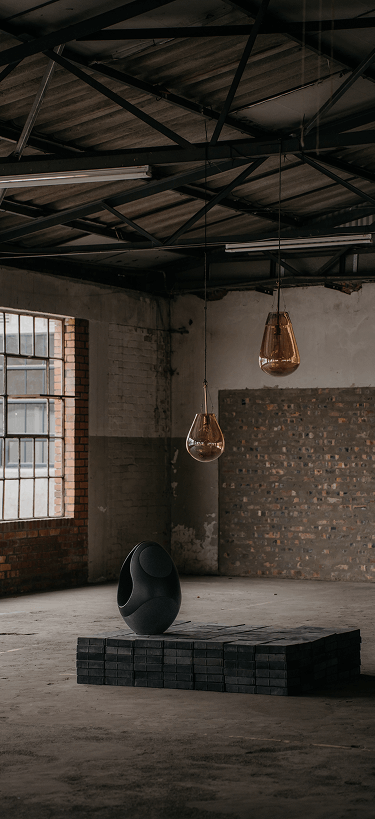 Pantheone I black wireless speaker on concrete pedestal with sculptural lighting