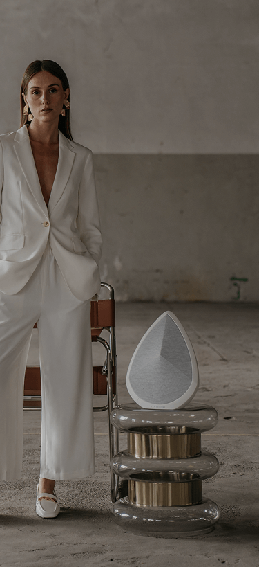 Obsidian white wireless speaker on stone platform in curated interior