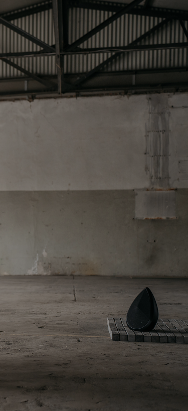 pantheone obsidian wireless speaker on bricks surfes in an indestrial space 