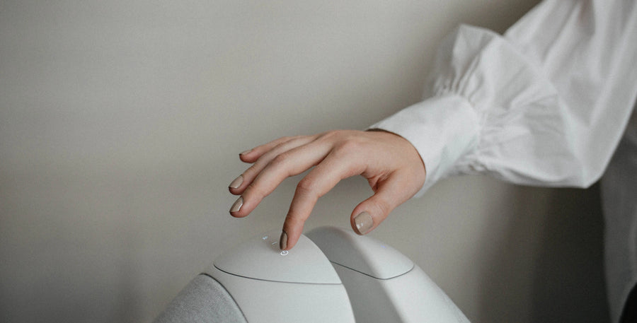A hand above the sculptural white Pantheone I speaker