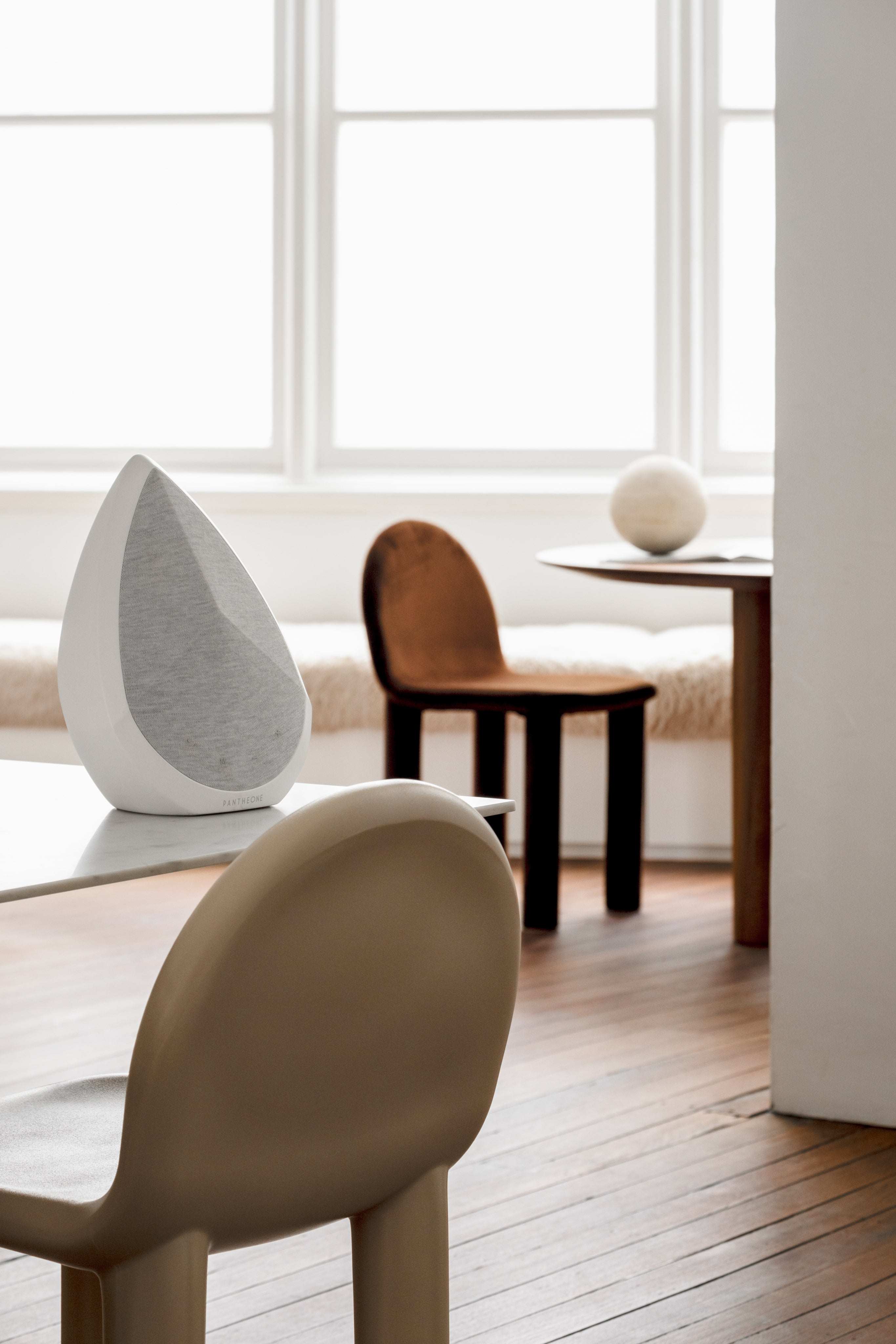 Obsidian white Bluetooth speaker on a dining table in a bright light room with design and stylish chairs
