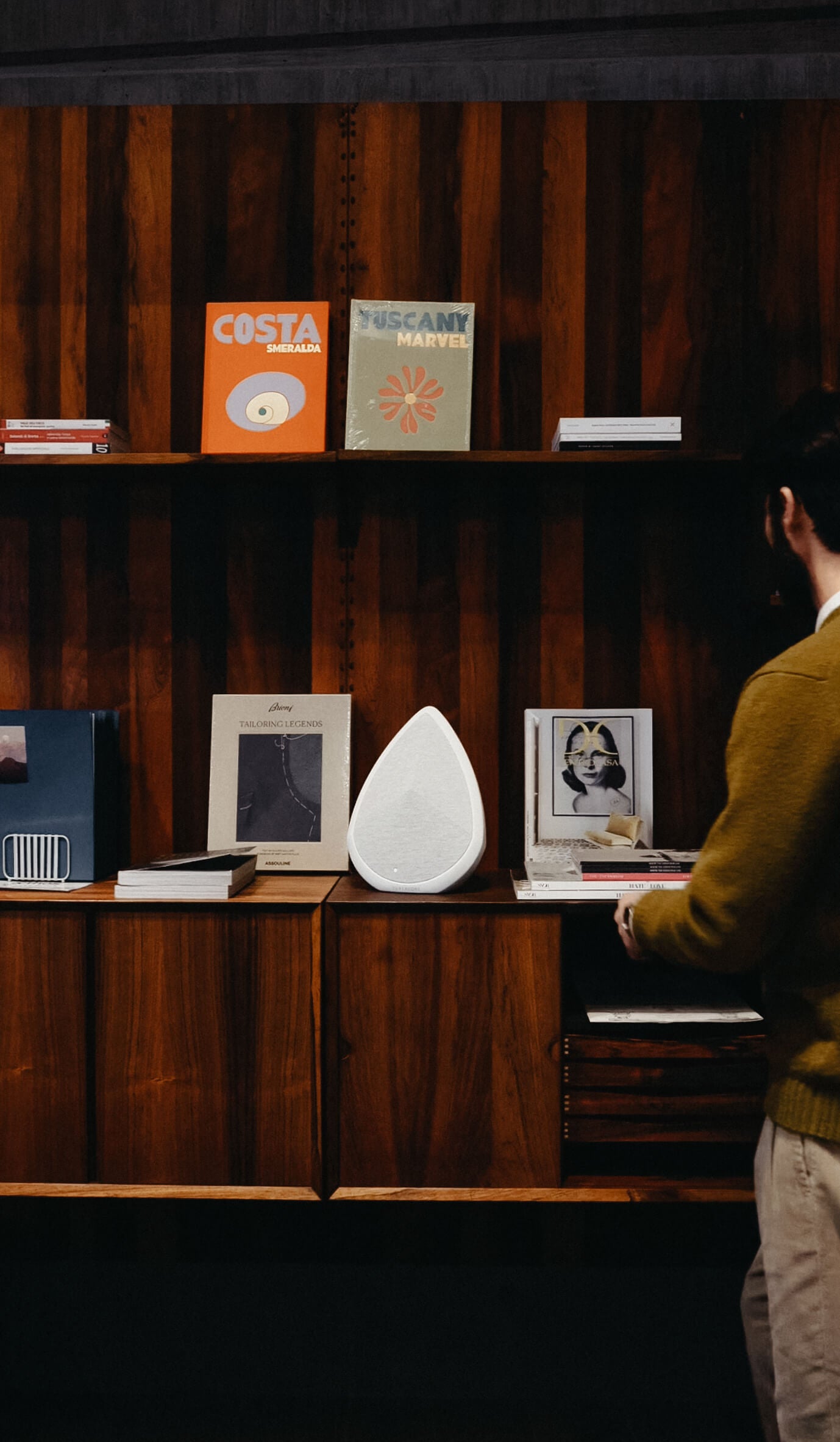 Pantheone Obsidian on a bookshelf playing music next to a man reading a magazine