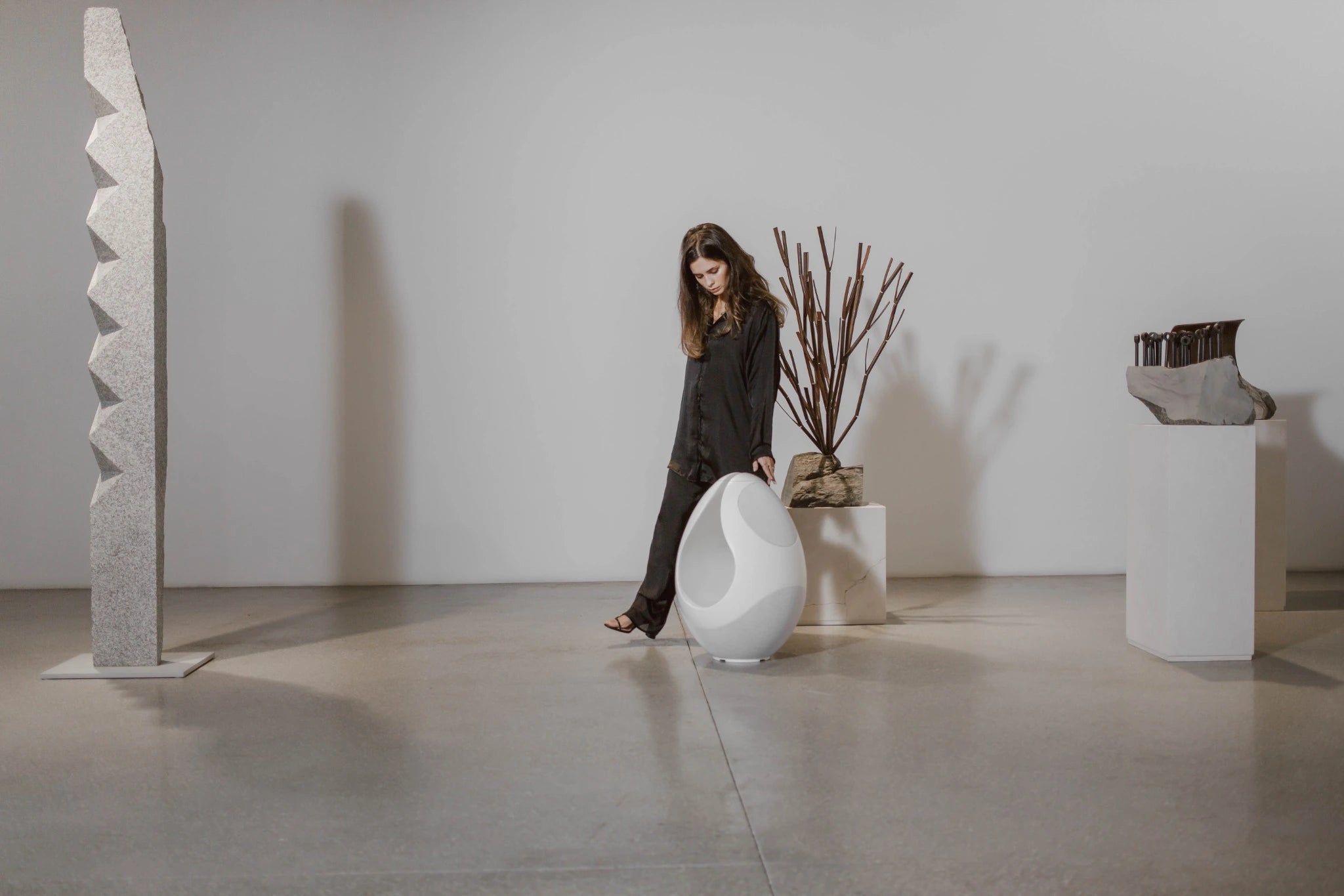 A model looking at the Pantheone I wireless speaker in a gallery. 
