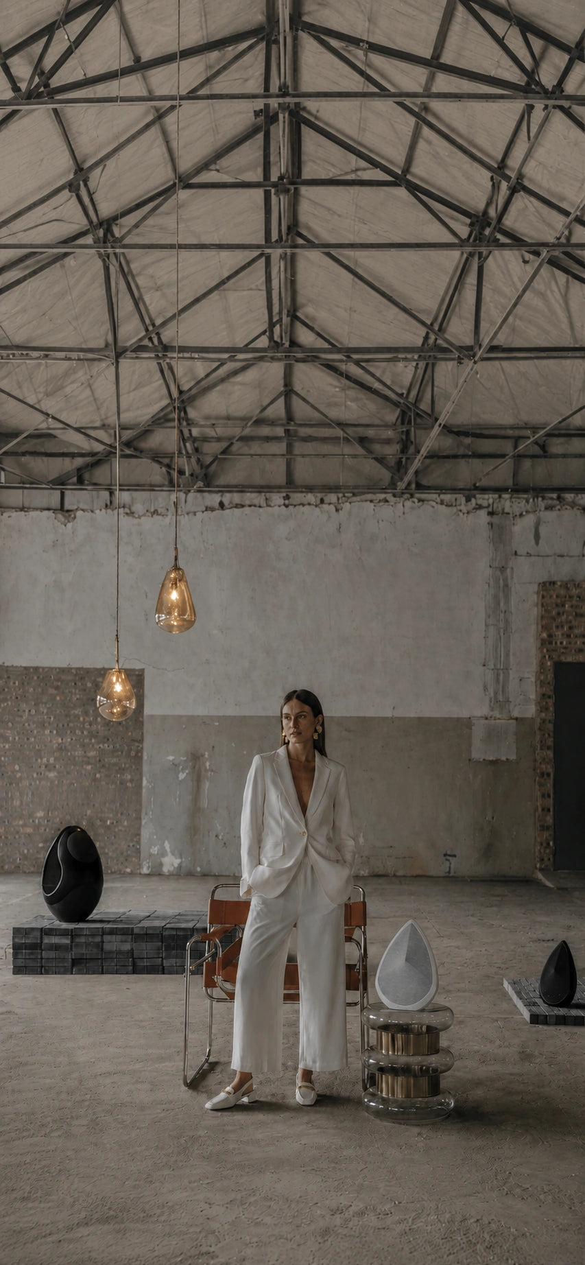 A person in a white outfit standing in an industrial-style room with the Pantheone wireless speakers.