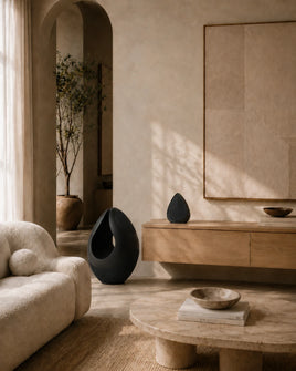 Modern living room with a wooden cabinet, the Pantheone I and Obsidian sculpture speakers, and a textured wall.