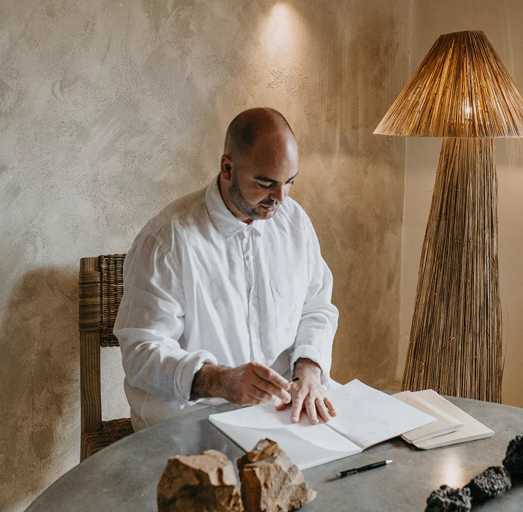 a man reading a book in next to a stylish floor lamp