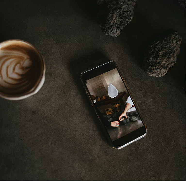 mobile phone showing the obsidian wireless speaker next to a cup of coffee and two stones 